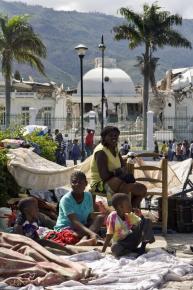 A family of earthquake survivors rests in an encampment facing the collapsed Presidential Palace